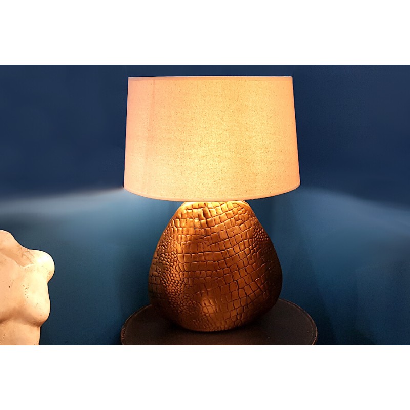 Lampe décorative allumée dans un salon, pied texturé croco, offrant une lumière douce.