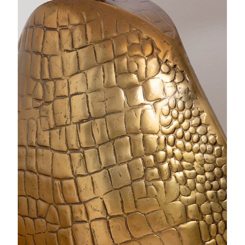 Gros plan sur le relief et la patine dorée du pied de lampe façon croco embossé.