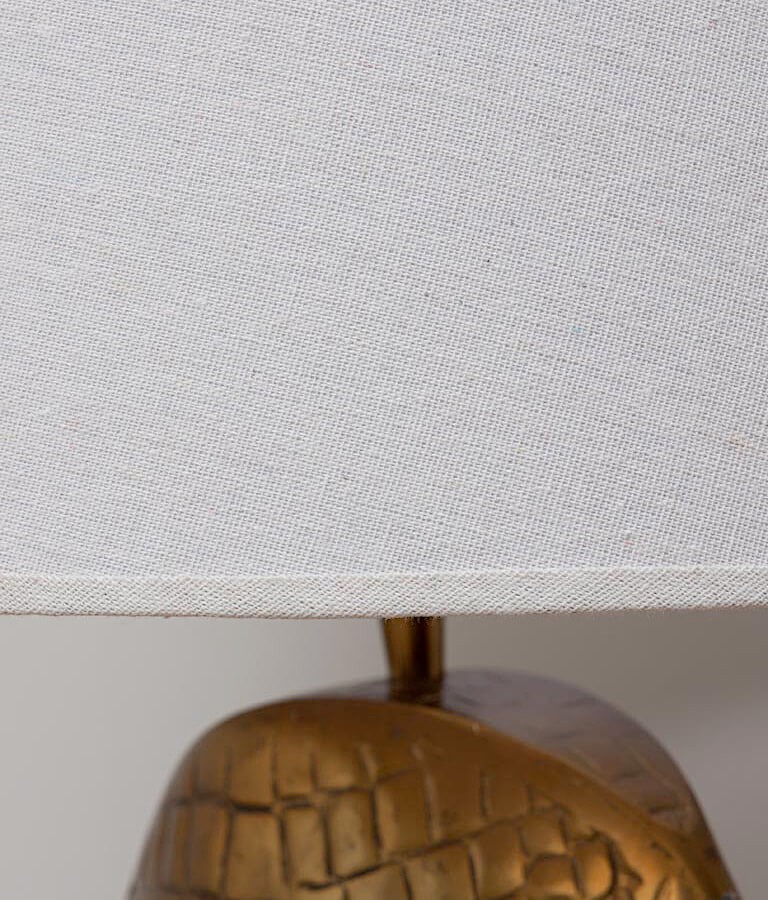 Gros plan sur l'abat-jour en lin beige de la lampe crocodile.
