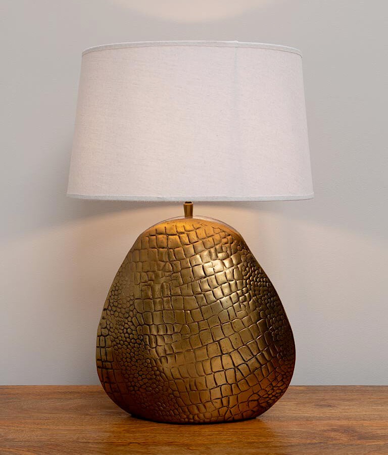 Lampe à poser avec pied doré effet peau de crocodile dans un intérieur moderne.