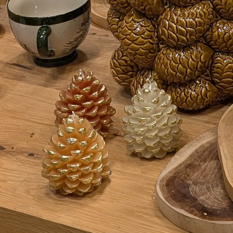 Composition festive de bougies pommes de pin sur un meuble en bois.