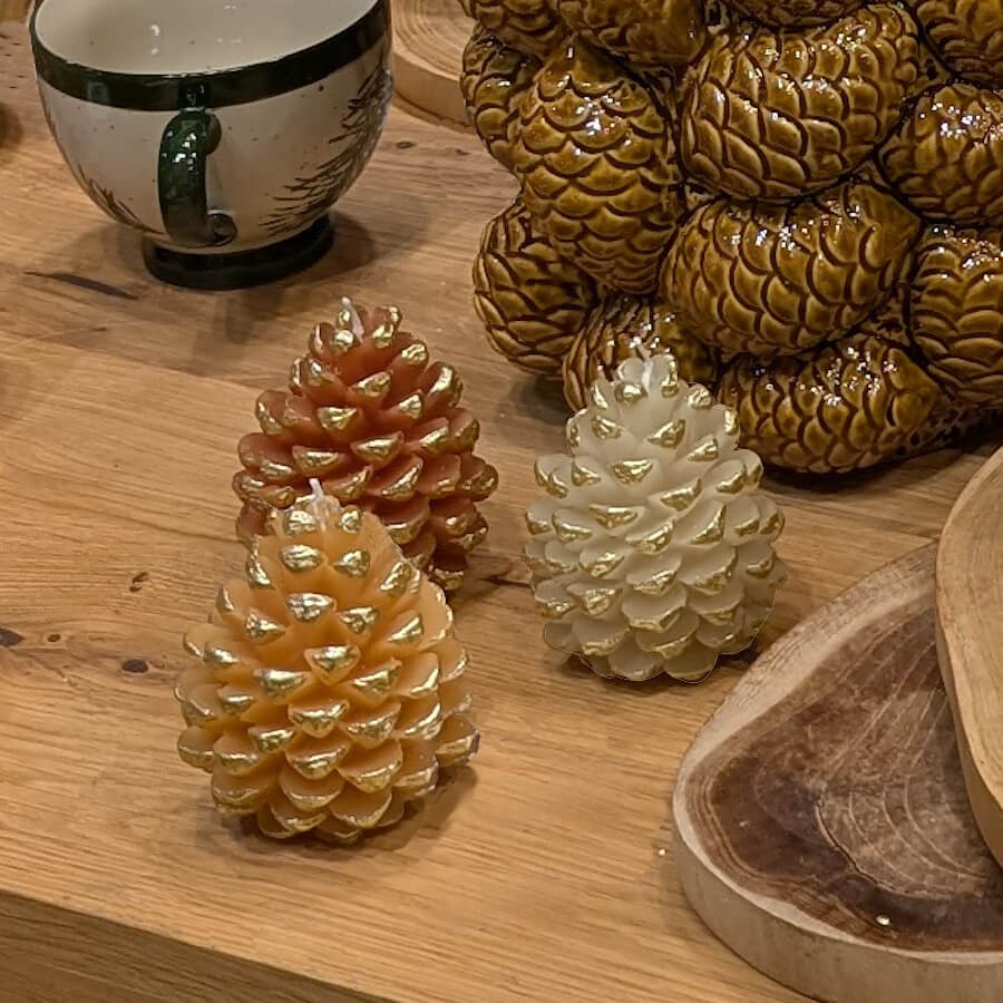 Composition festive de bougies pommes de pin sur un meuble en bois.