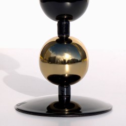 Gros plan sur la sphère dorée et la finition noir brillant du bougeoir.