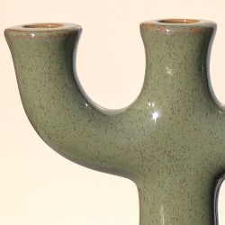 Gros plan sur l'émail vert sauge moucheté et la forme fluide du chandelier.