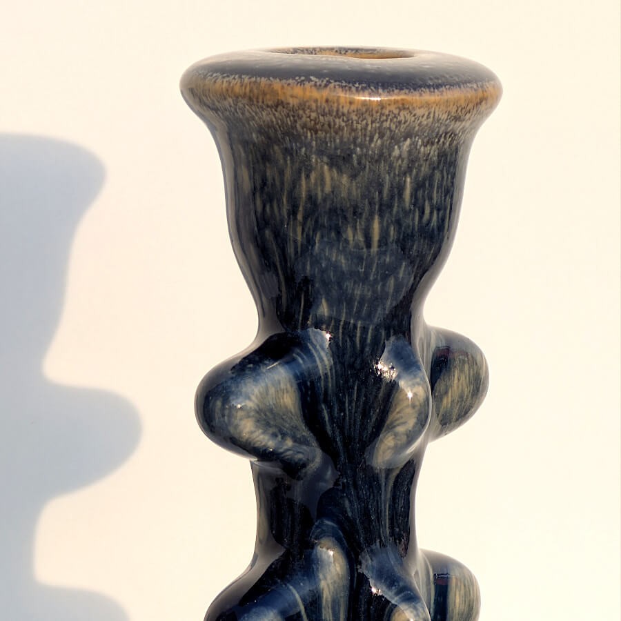 Gros plan sur l'émaillage bleu marine coulant et la forme torsadée.