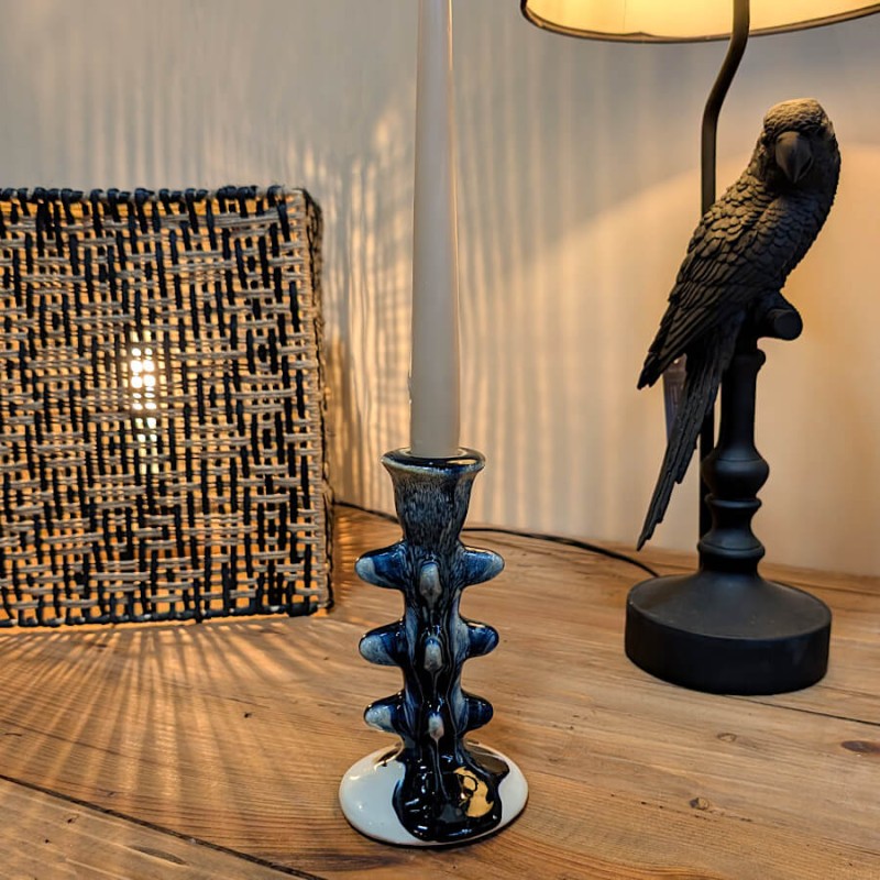 Bougeoir sculptural bleu marine posé sur une console sombre, ambiance chic.