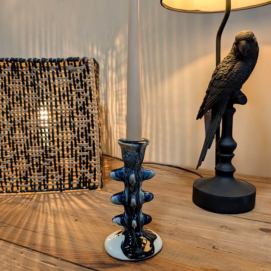 Bougeoir sculptural bleu marine posé sur une console sombre, ambiance chic.