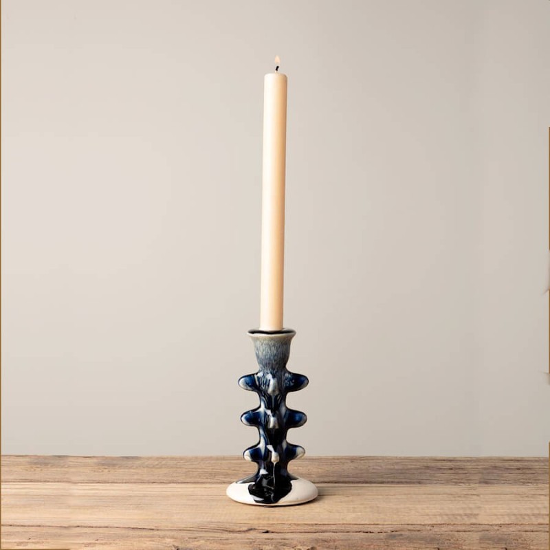Bougeoir en céramique torsadé avec une bougie chandelle blanche.
