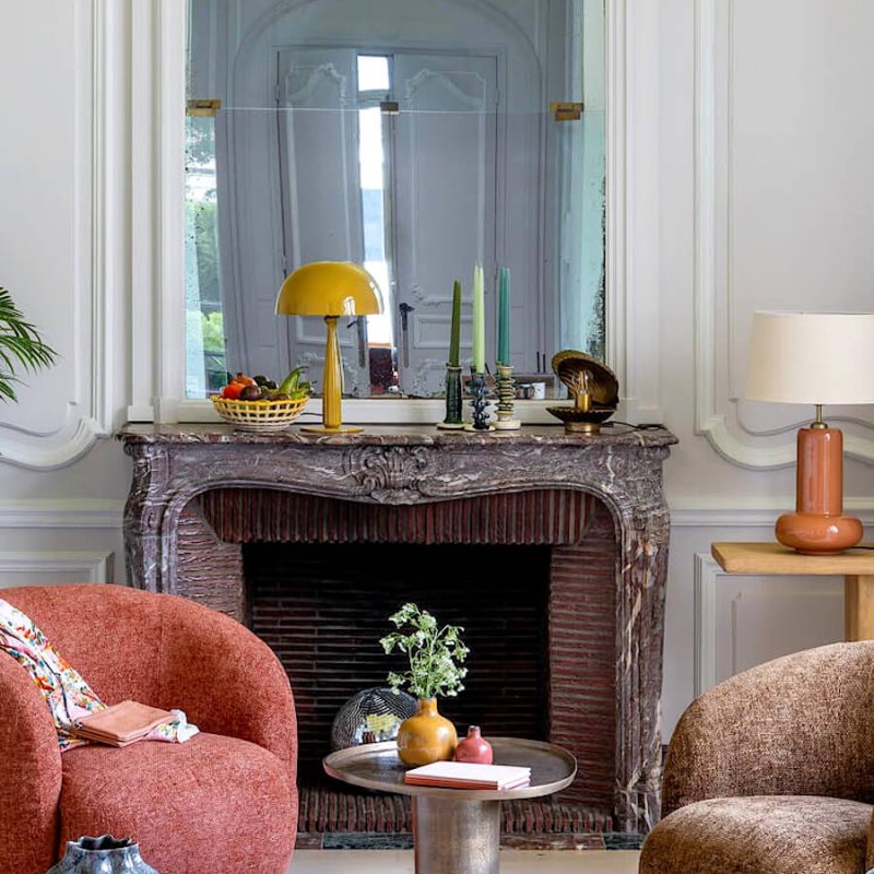 Bougeoir sculptural dans un salon chic, près d'une cheminée en marbre.