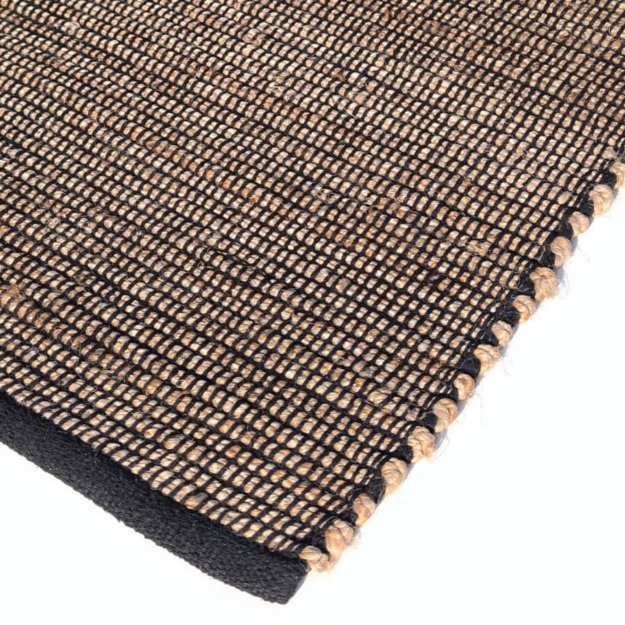 Détail de la finition et de la bordure noire du tapis en jute et coton.