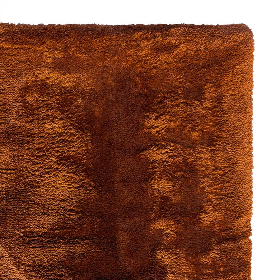 Focus sur la fibre ultra douce et le coloris taupe profond du tapis.