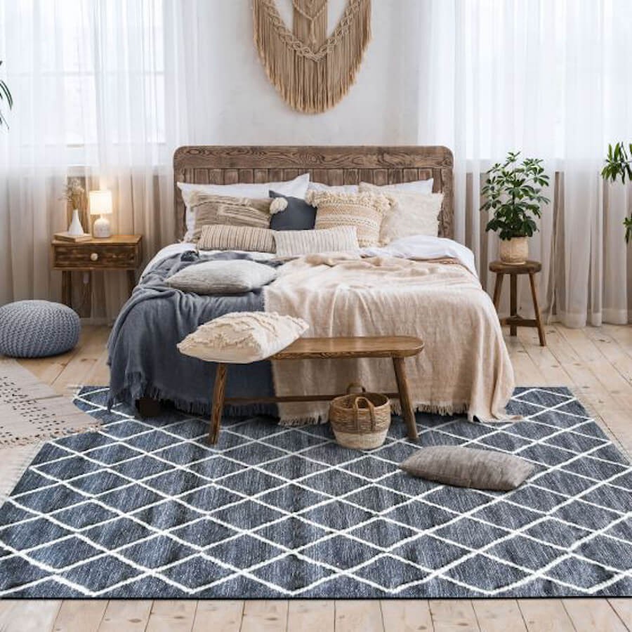 Tapis gris anthracite aux losanges en laine épaisse brute, utilisé en descente de lit pour une ambiance zen et naturelle.