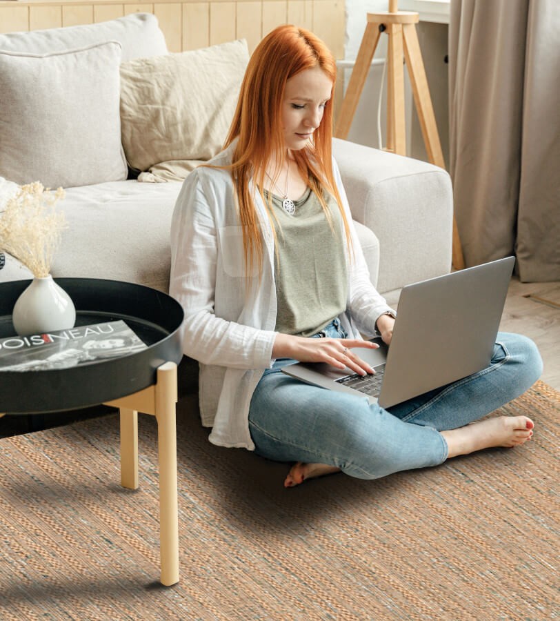 Femme assise sur le tapis d'intérieur naturel et confortable, pour un espace de travail cosy.