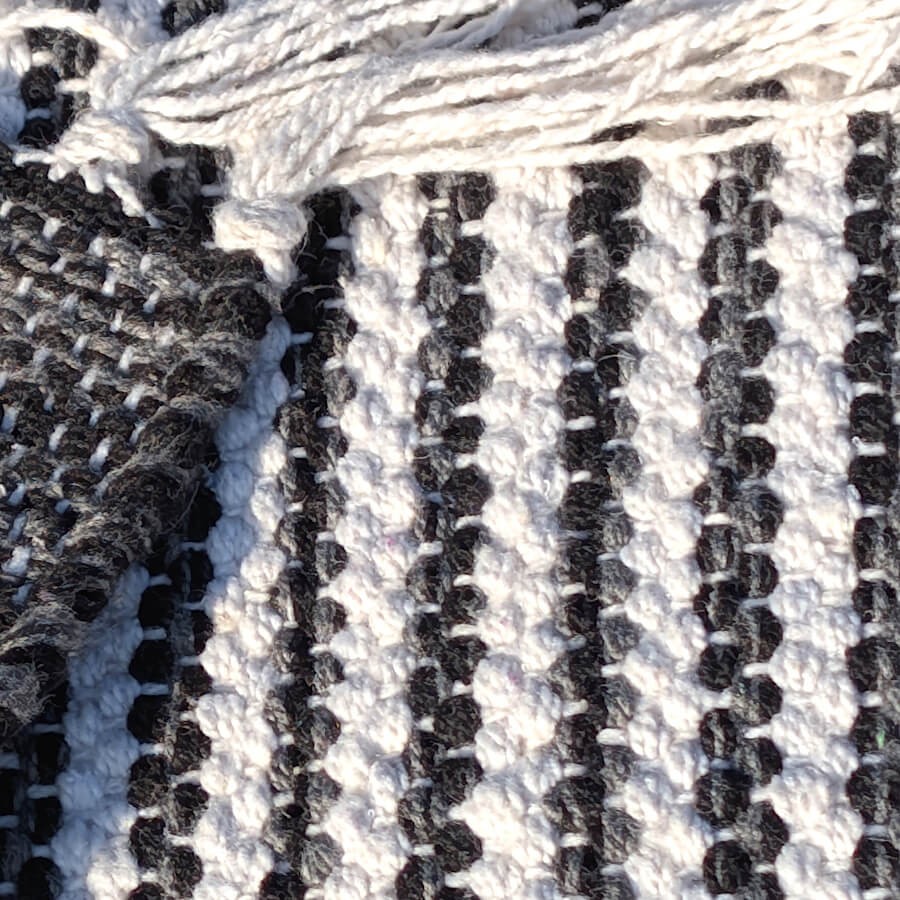 Zoom sur la qualité du tissage plat et les fibres de coton du tapis noir et blanc.