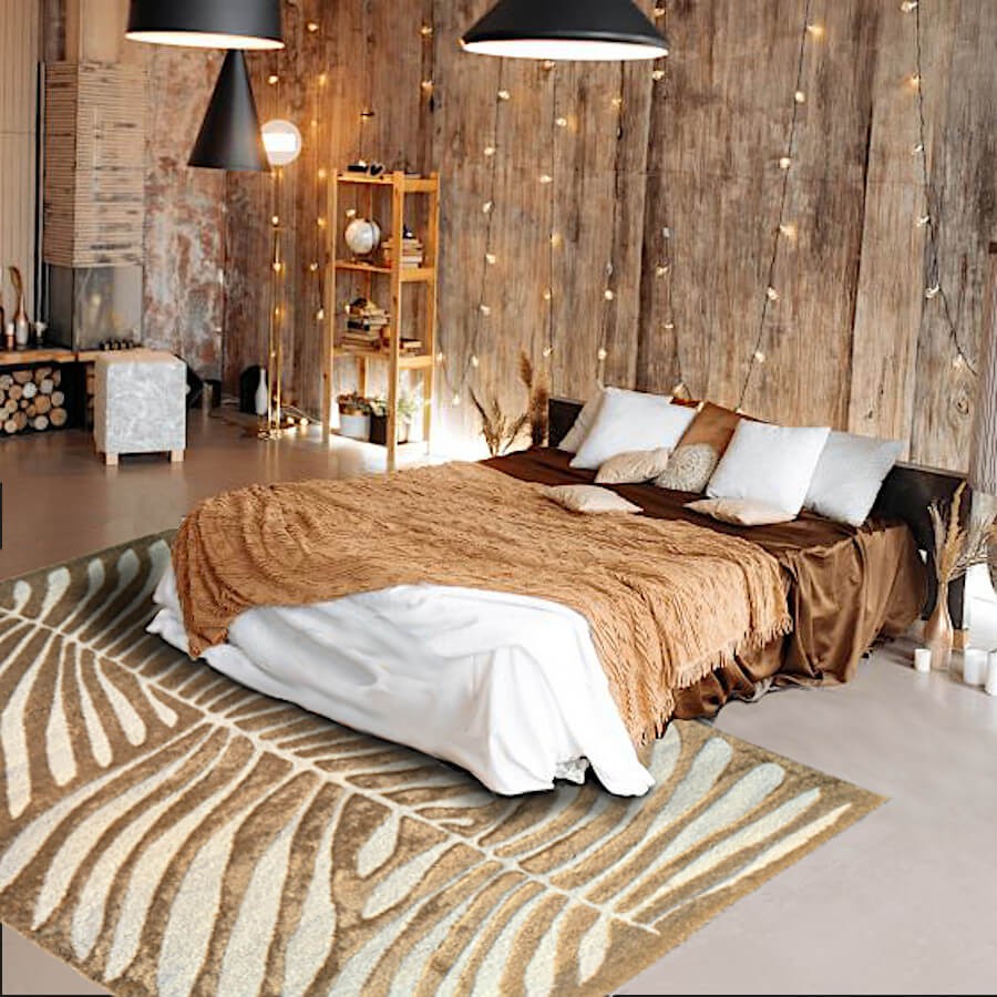 Tapis beige à motif feuillage utilisé en descente de lit dans une chambre au style chaleureux.