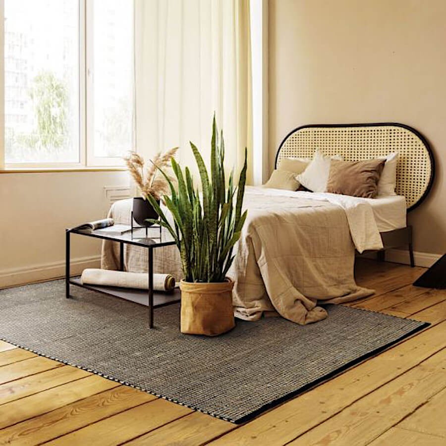 Tapis en jute et coton noir apportant une touche naturelle élégante à une chambre.
