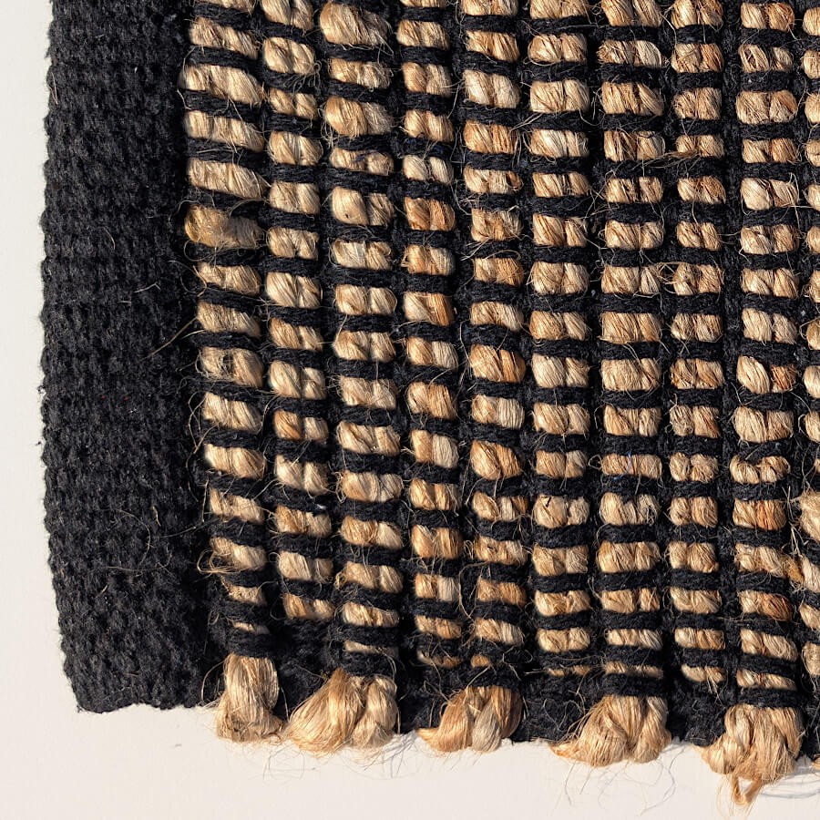 Gros plan sur le relief des fibres de jute et les finitions en coton noir.