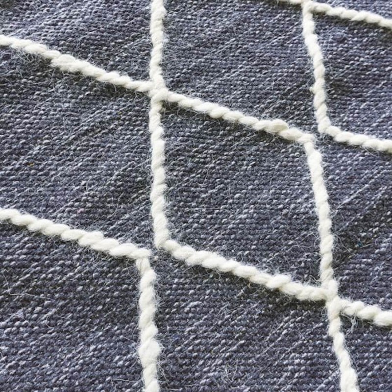 Détail du motif géométrique en laine épaisse sur fond coton.