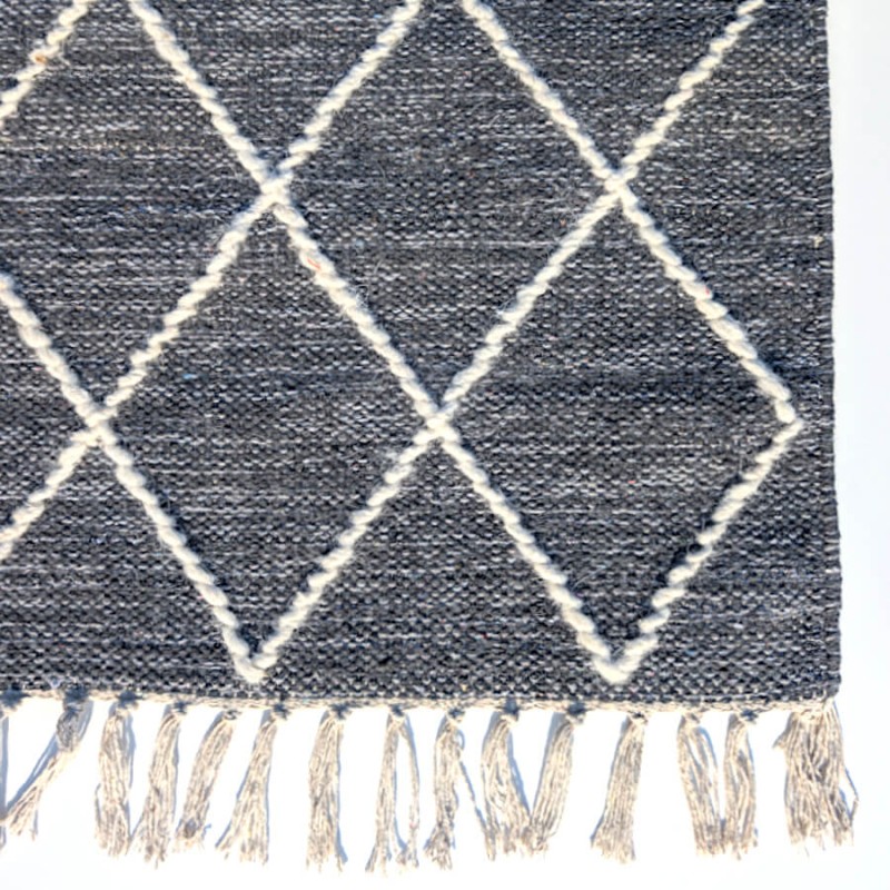 Finitions artisanales avec franges délicates en coton et laine.