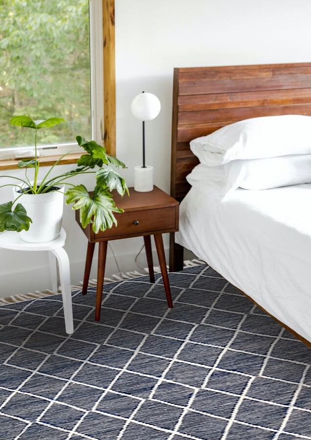 Tapis gris foncé à losanges écrus, utilisé en descente de lit, dans une ambiance cosy.