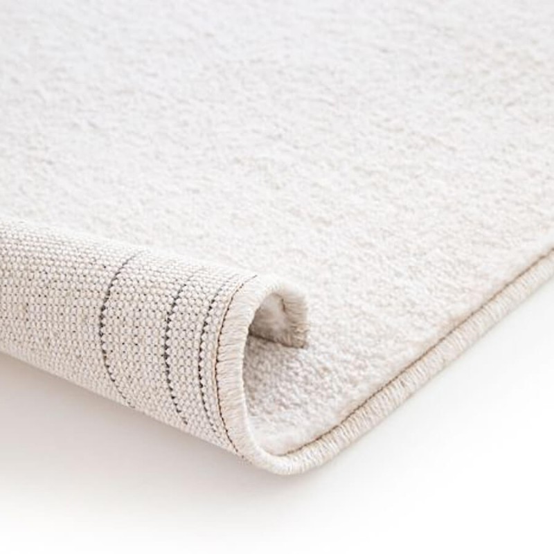 Vue sur la souplesse du rebord et l'épaisseur du tapis aux formes géométriques abstraites.