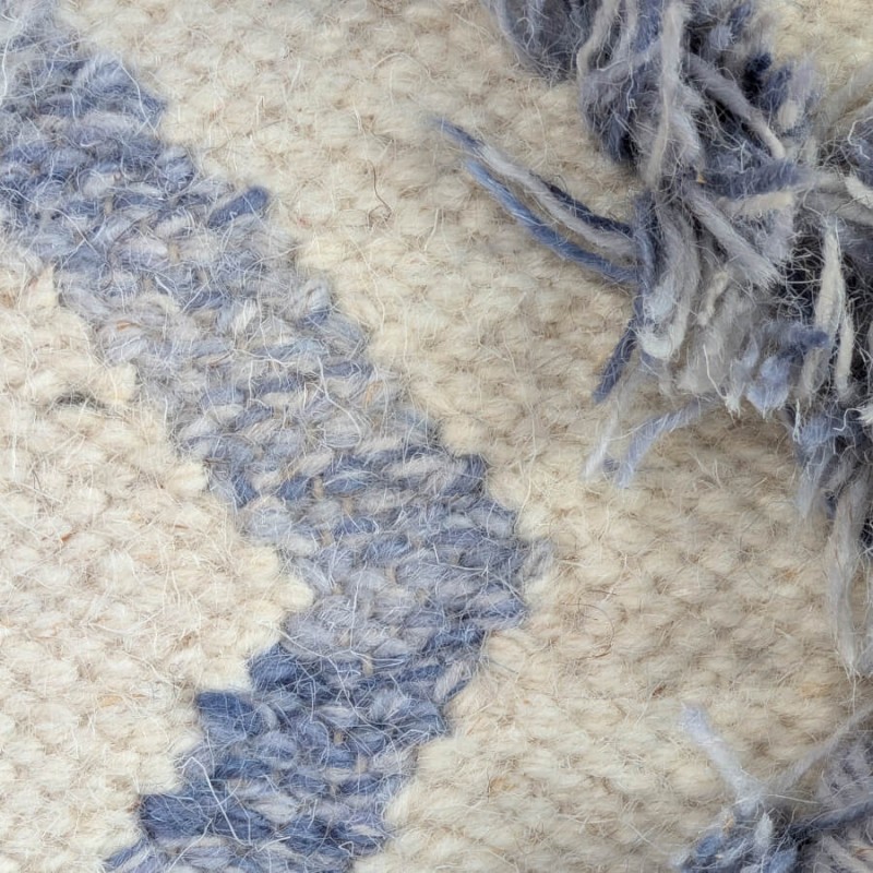 Détail du tissage en relief et des fils de laine bleus effilochés.