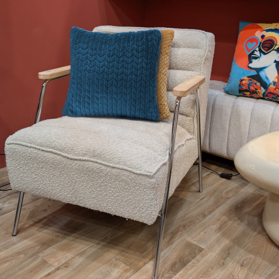 Mise en scène du coussin bleu pétrole sur une assise moderne en tissu bouclé.