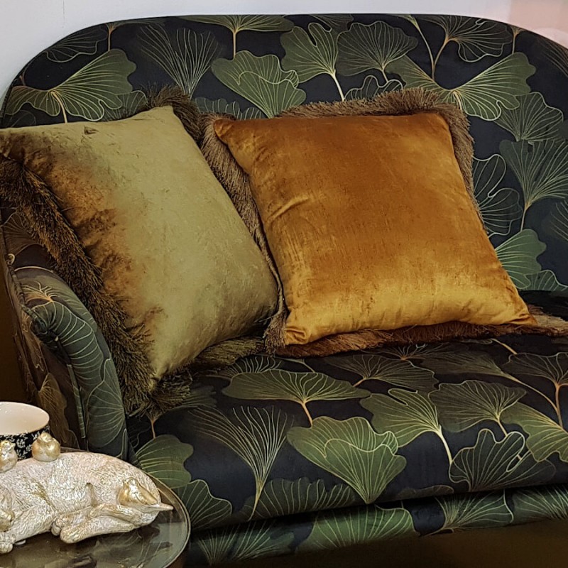 Le coussin Kaki disposé sur un canapé à motifs tropicaux pour un look botanique.