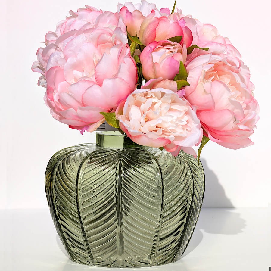 Vase vert texturé garni de pivoines roses pour un contraste printanier. Retrouvez le bouquet de pivoines dans notre catalogue.