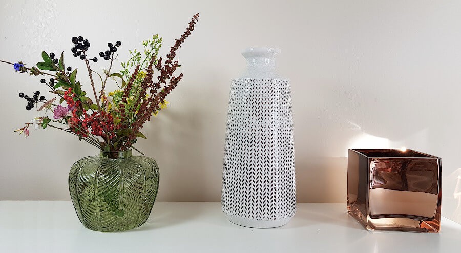 Présentation du vase sur une étagère blanche avec d'autres objets déco design.