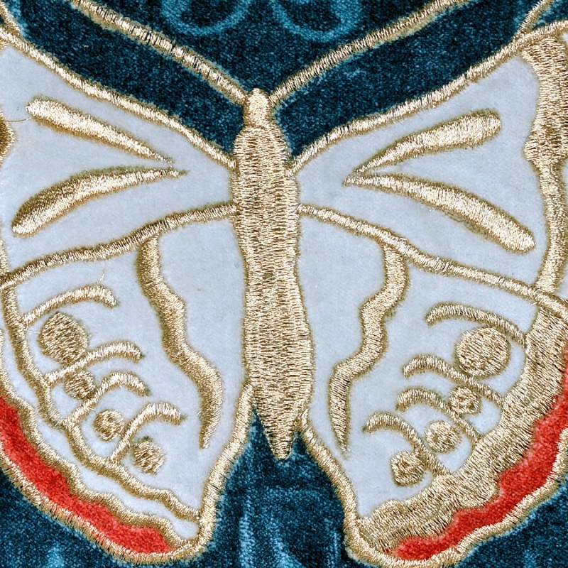 Zoom sur la qualité des broderies fleurs et papillon aux nuances ocre et brique.