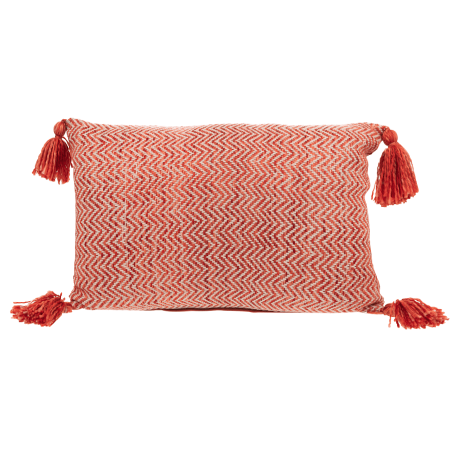 Coussin rectangulaire tissé corail et beige avec quatre pompons aux angles.
