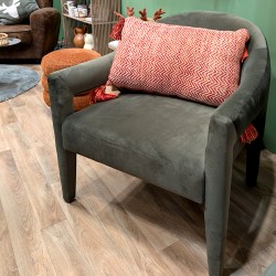Coussin bohème corail posé sur un fauteuil gris moderne pour un contraste chaleureux.