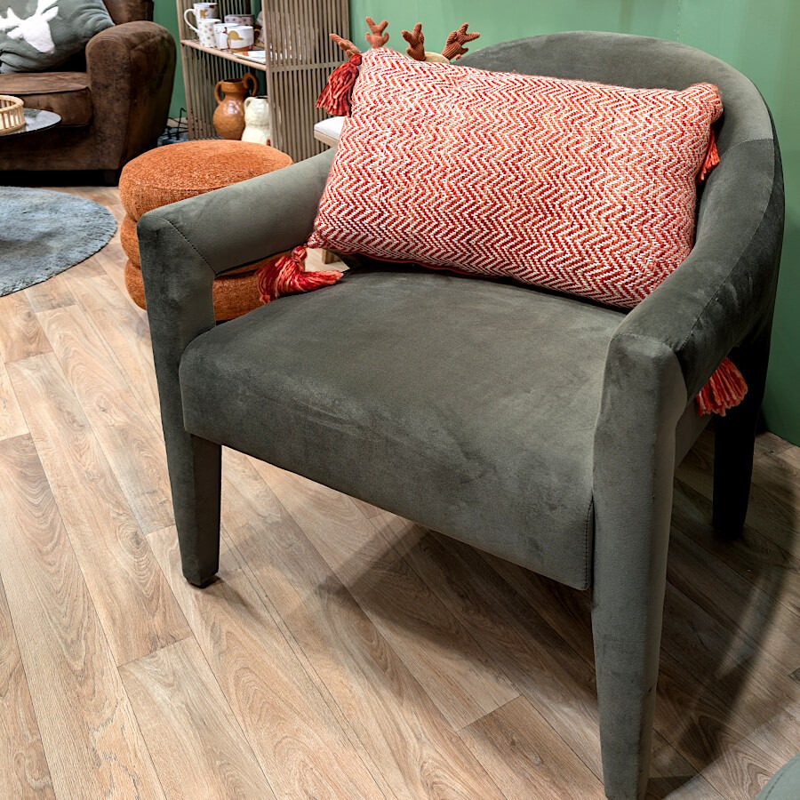 Coussin bohème corail posé sur un fauteuil gris moderne pour un contraste chaleureux.