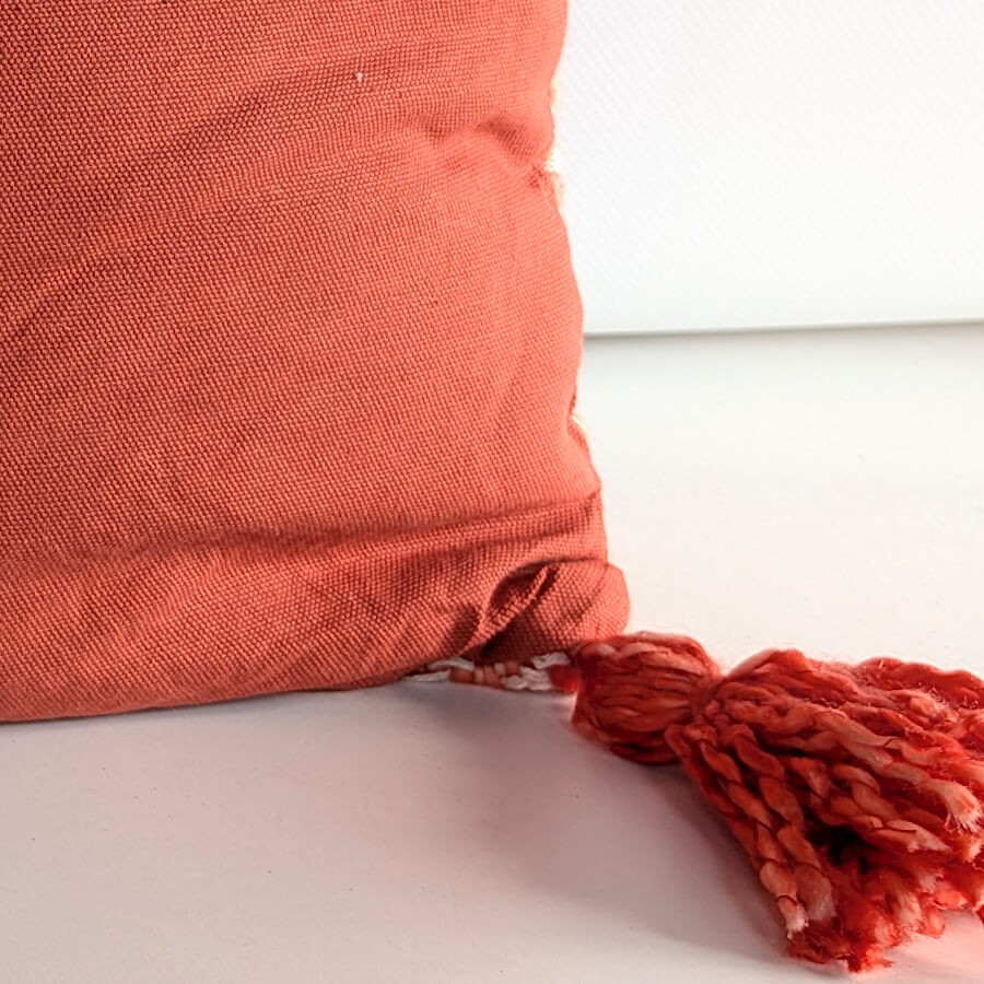 Vue de l'arrière du coussin en tissu uni corail avec fermeture invisible.