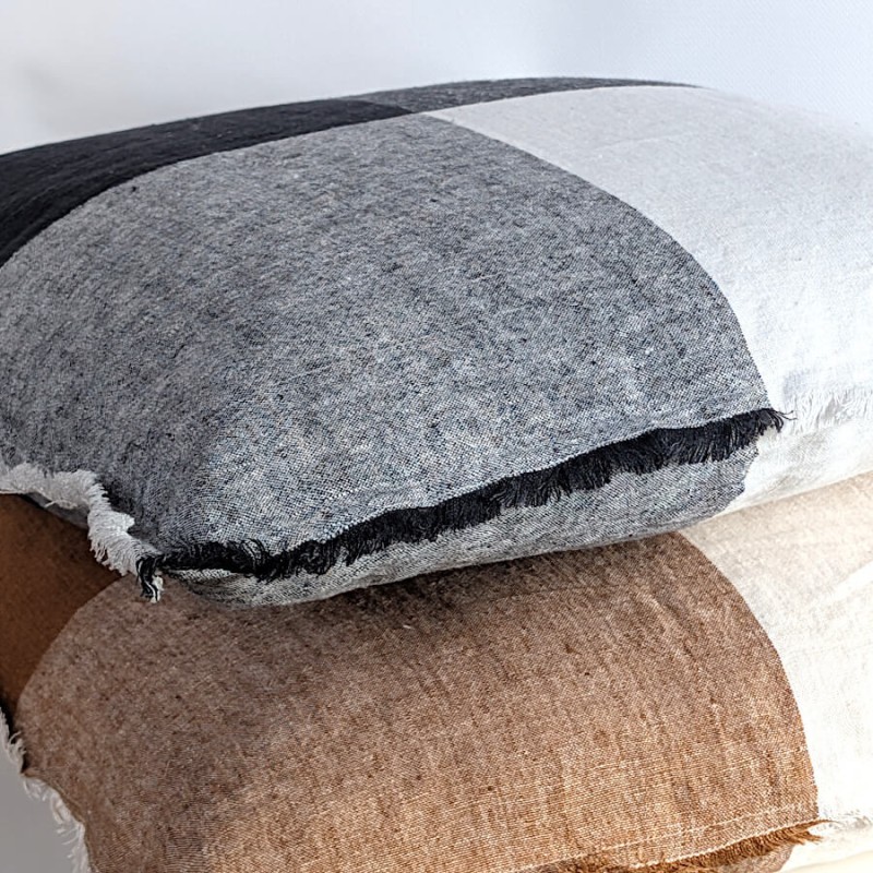 Vue de profil montrant l'épaisseur et le gonflant du coussin damier noir et blanc, posé sur une variante marron et blanc.