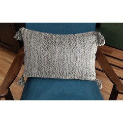Coussin gris texturé posé sur un fauteuil bleu pour une ambiance moderne.