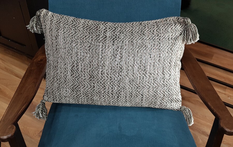 Coussin gris texturé posé sur un fauteuil bleu pour une ambiance moderne.