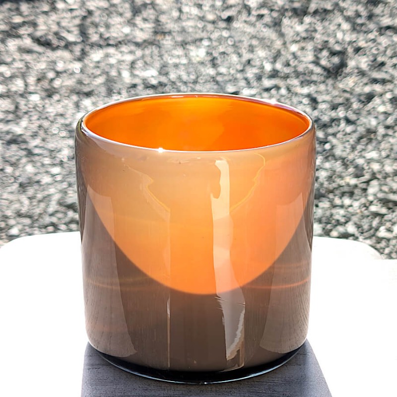 Photophore gris et orange posé sur une surface brillante.