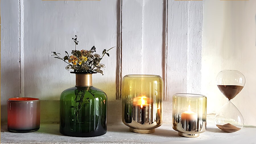 Ensemble décoratif avec vases en verre, photophores et sablier.