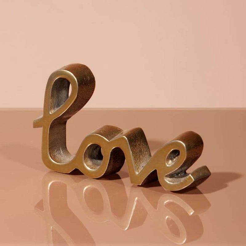 Vue de profil montrant l'épaisseur de 2 cm de la décoration Love en métal doré.