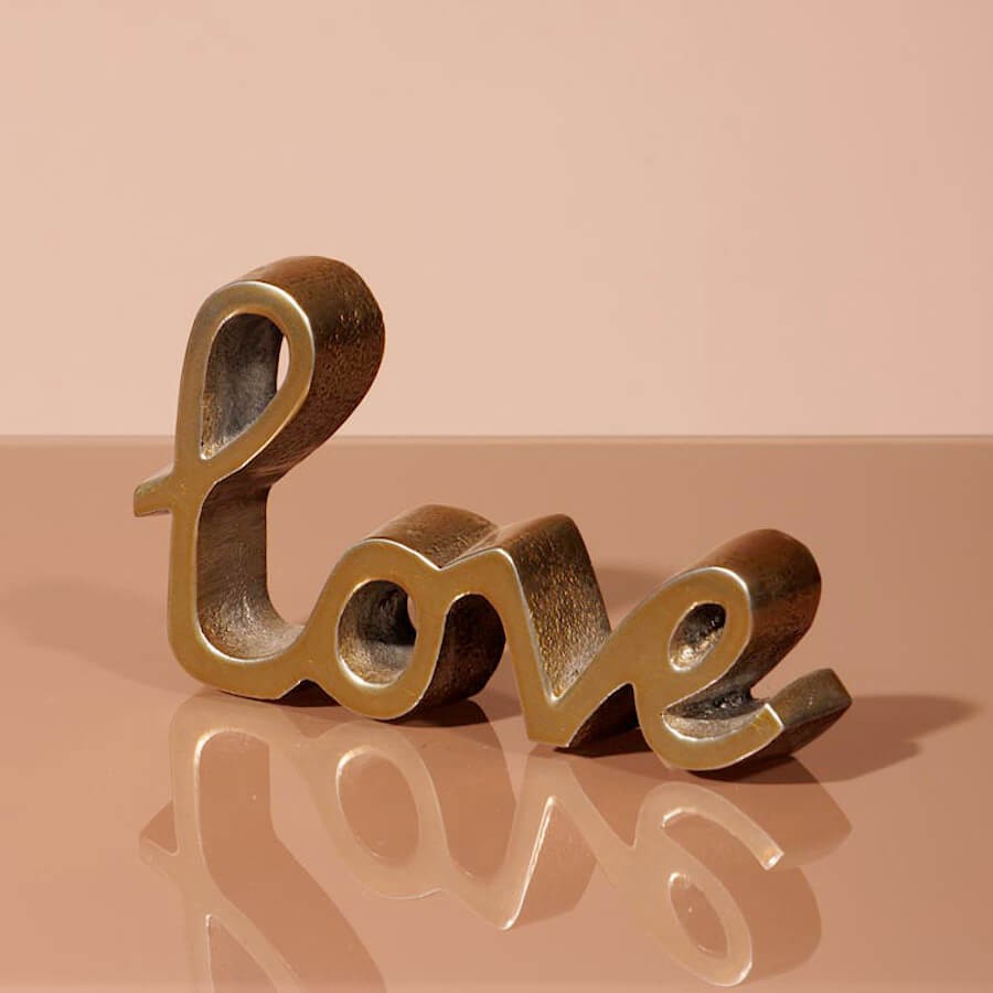 Vue de profil montrant l'épaisseur de 2 cm de la décoration Love en métal doré.