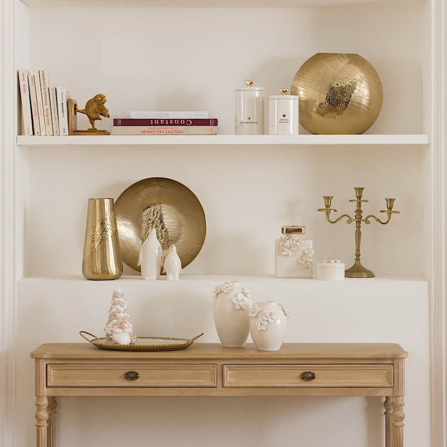 Vase en porcelaine blanche sur une étagère avec accessoires dorés chics.