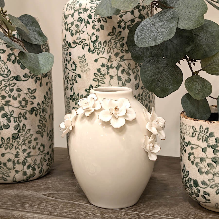 Vase fleuri posé sur un buffet à côté d'eucalyptus.