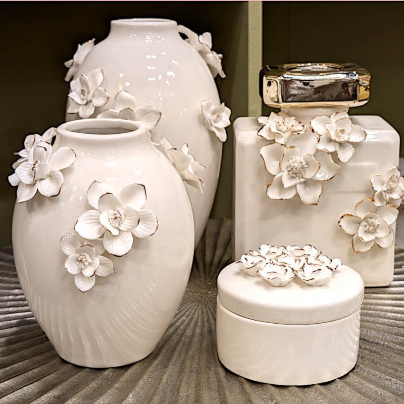 Composition de vases fleuris et flacon de parfum blanc.