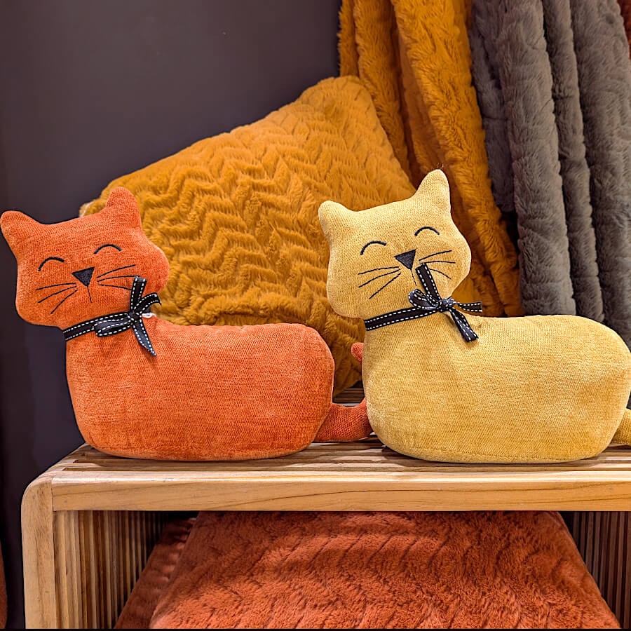 Duo de cale-portes chats terracotta et jaune moutarde sur une étagère.
