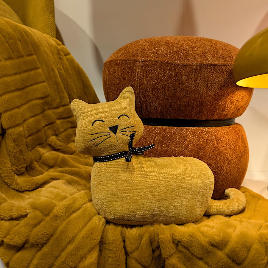 Cale-porte chat moutarde mis en scène avec des textiles chauds.