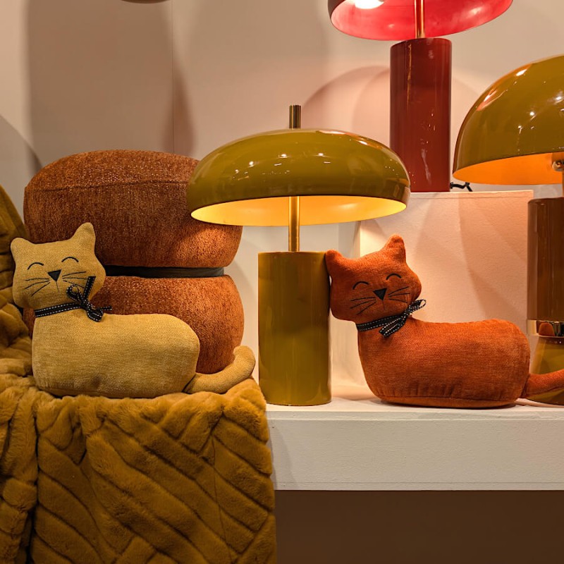 Chat lesté jaune et son pendant terracotta près d'une lampe design vintage.