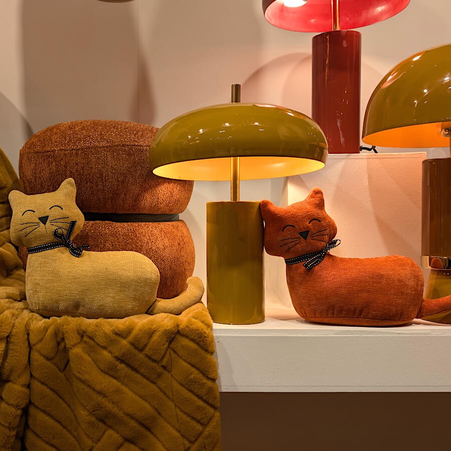 Chat lesté jaune et son pendant terracotta près d'une lampe design vintage.