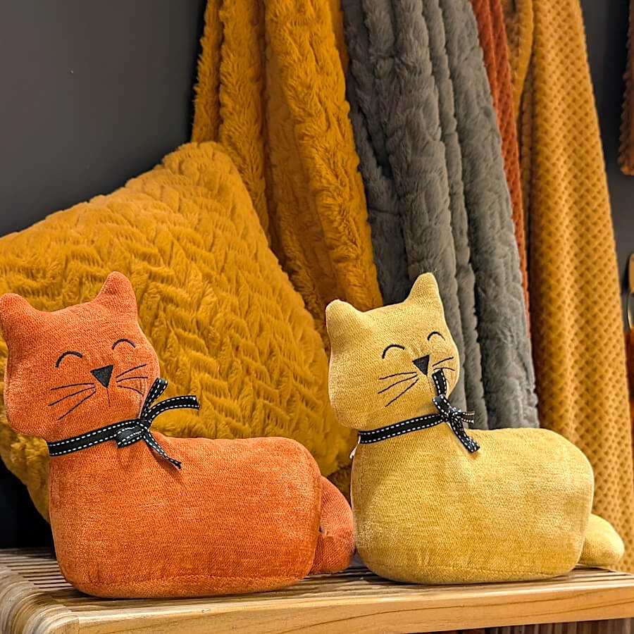 Duo de chats décoratifs moutarde et terracotta sur une console.